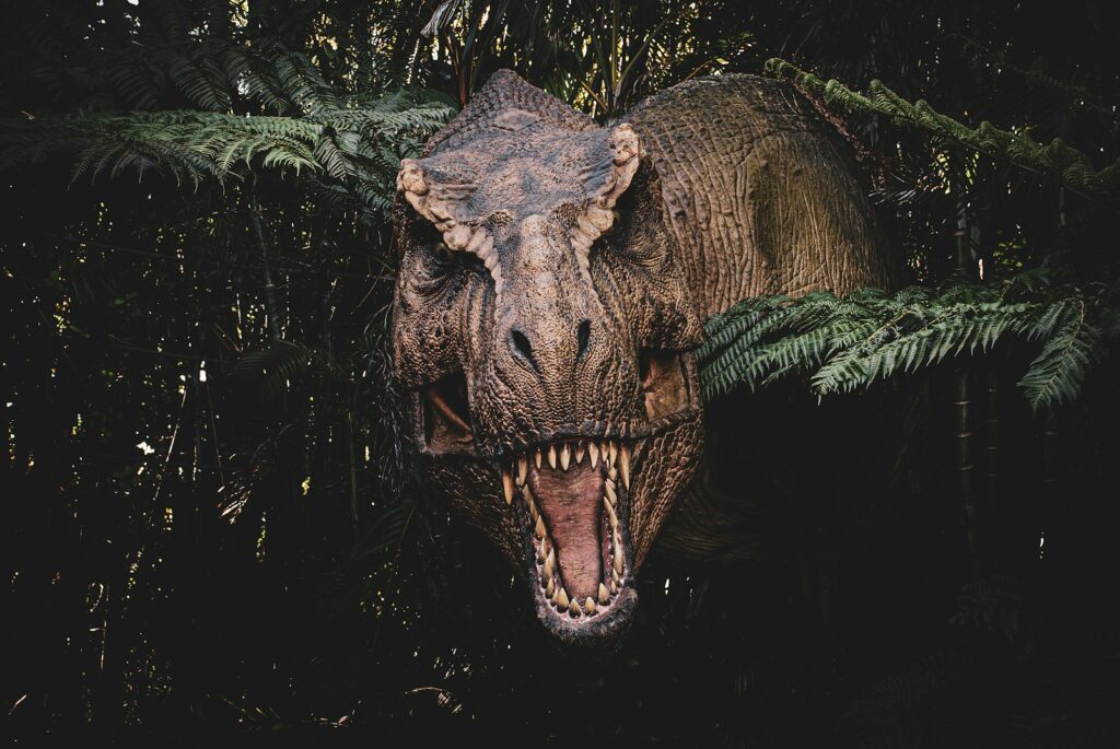 Dinosaurio con la boca abierta en un bosque, ambiente de las películas de Jurassic World