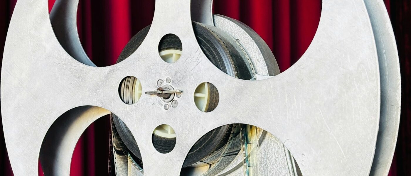Bobina de un proyector de cine antiguo con una cortina roja de fondo
