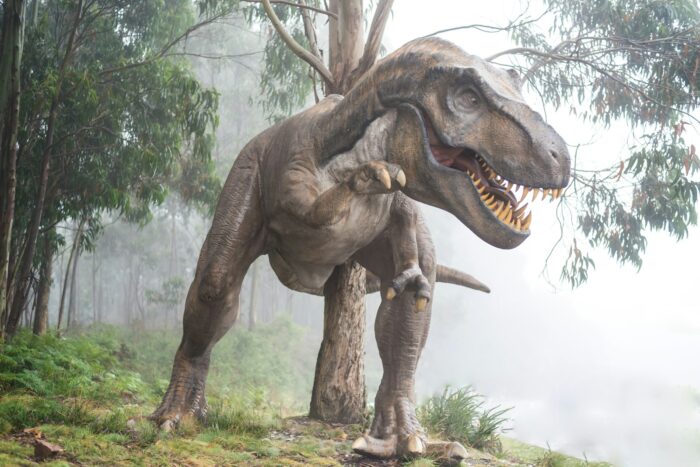 Modelo de tiranosaurio rex en un bosque con niebla, imagen de la saga Jurassic Park