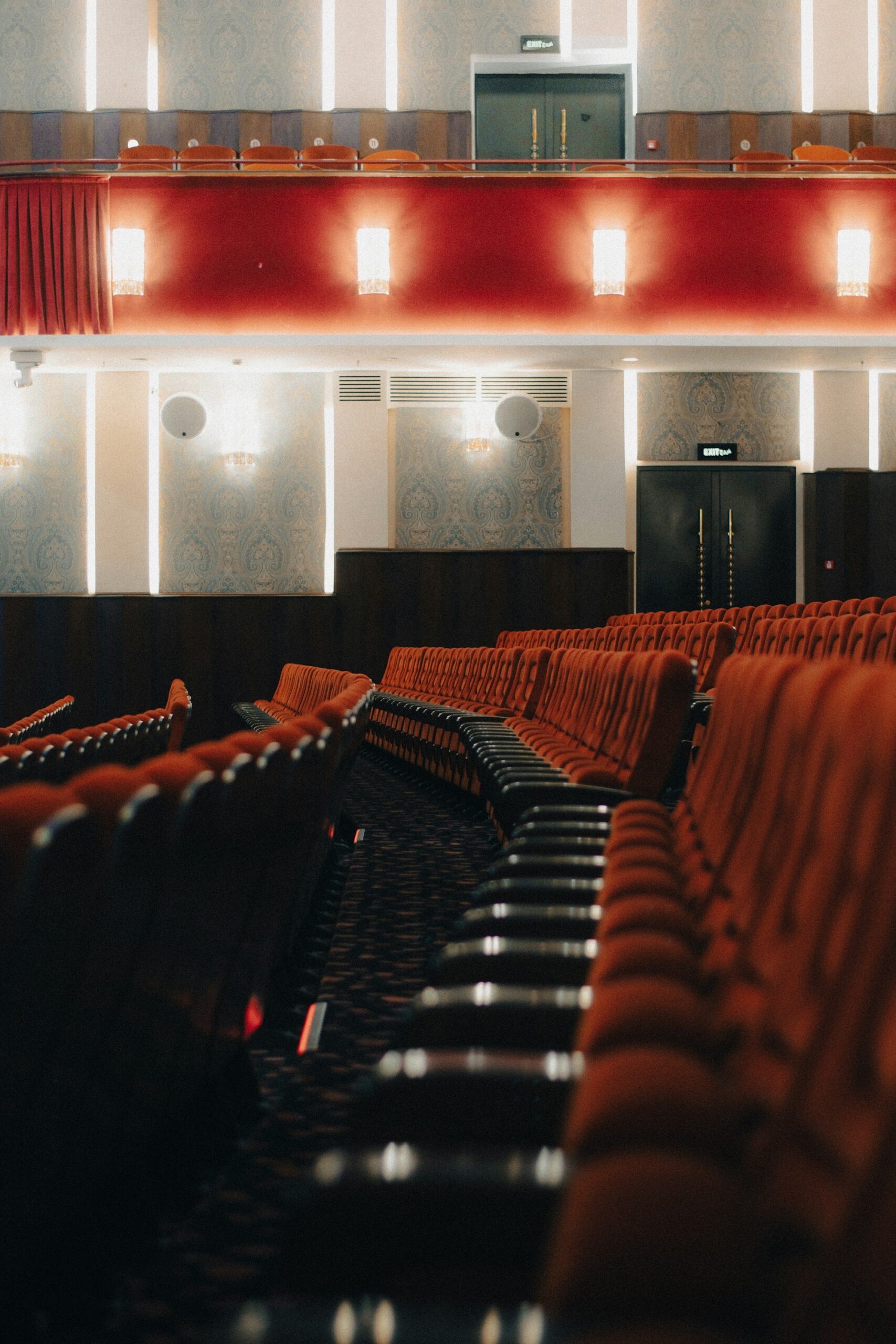 Sala de cine clásica con butacas de terciopelo rojo vacías frente a la pantalla